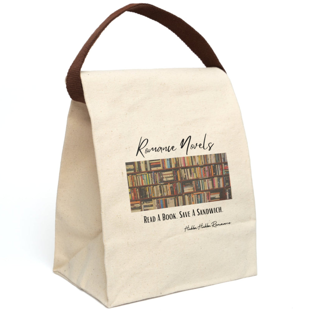 This canvas lunch bag features a full-color image of wooden bookshelves filled with dozens of romance novels and paperbacks in a library-style setting. Above the image, the words “Romance Novels” are written in a flowing black script. Below the bookshelves, bold black lettering reads: “Read A Book. Save A Sandwich.” The bag has a roll-top closure and a sturdy canvas carrying strap which is displayed upright.