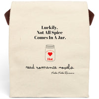 This canvas lunch bag features a natural canvas background with bold black typography. At the top, large black text reads: “Luckily, Not All Spice Comes In A Jar.” Below is a simple drawing of a mason jar with a red heart in the center. At the top of the jar, curved text reads: “Extra Extra Extra,” and beneath the heart, the word “Hot” appears in red. At the bottom of the design, cursive black script reads: “read romance novels.” The bag includes a velcro closing and canvas handle for carrying.