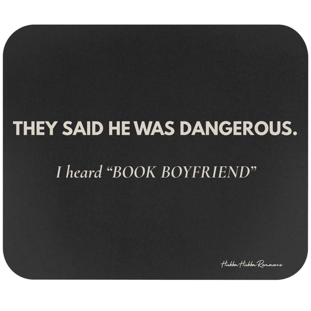 A dark gray rectangular mouse pad with rounded corners featuring the quote 'THEY SAID HE WAS DANGEROUS. I heard ‘BOOK BOYFRIEND’' in cream text.