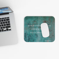 A rectangular mouse pad with rounded corners featuring a distressed teal and green textured background, white printed text, and a white mouse cutout. A silver laptop is partially visible on the left on a clean white surface.