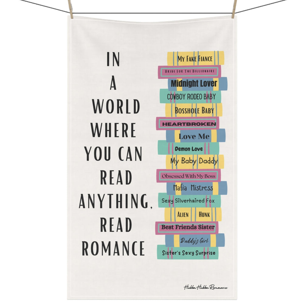 The image features a cotton kitchen towel with a colorful stack of romance books on the right, accompanied by a column of vertical text to the left that reads: 'In a World Where You Can Read Anything, Read Romance.' The towel is displayed on a clothesline.
