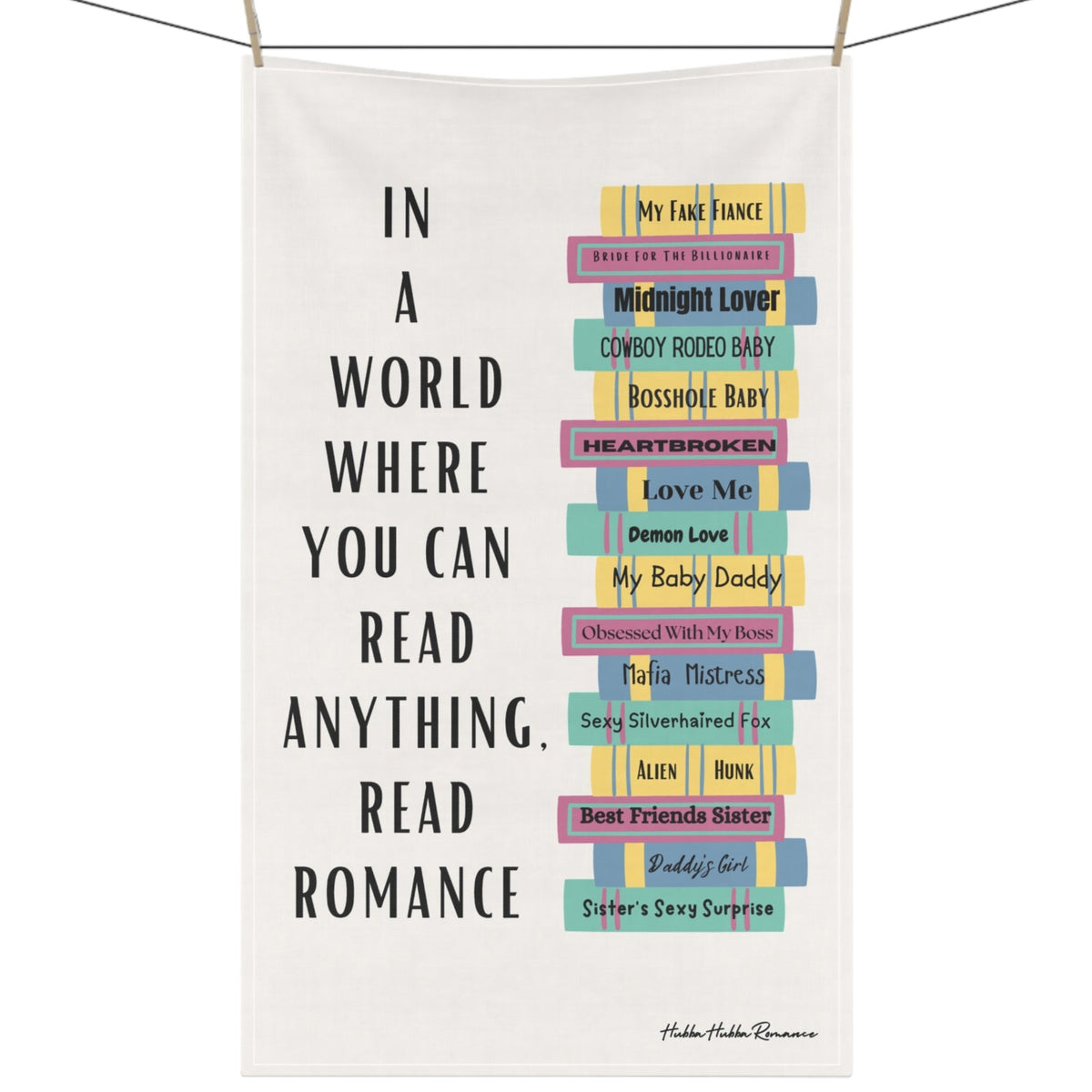 The image features a cotton kitchen towel with a colorful stack of romance books on the right, accompanied by a column of vertical text to the left that reads: 'In a World Where You Can Read Anything, Read Romance.' The towel is displayed on a clothesline.
