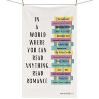 The image features a cotton kitchen towel with a colorful stack of romance books on the right, accompanied by a column of vertical text to the left that reads: 'In a World Where You Can Read Anything, Read Romance.' The towel is displayed on a clothesline.

