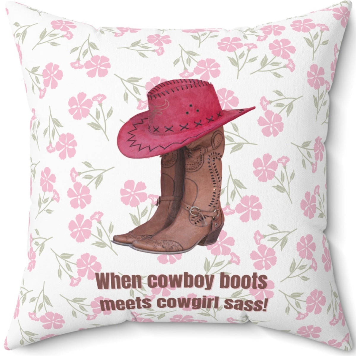 This 20 inch square pillow features a pair of brown leather cowboy boots with intricate stitching and metal accents, topped with a red cowboy hat with black stitched detailing. The background is soft white with a delicate pink floral pattern. Below the boots and hat, the bold brown text reads: "When cowboy boots meets cowgirl sass!" The design combines Western charm with a playful, feminine flair.