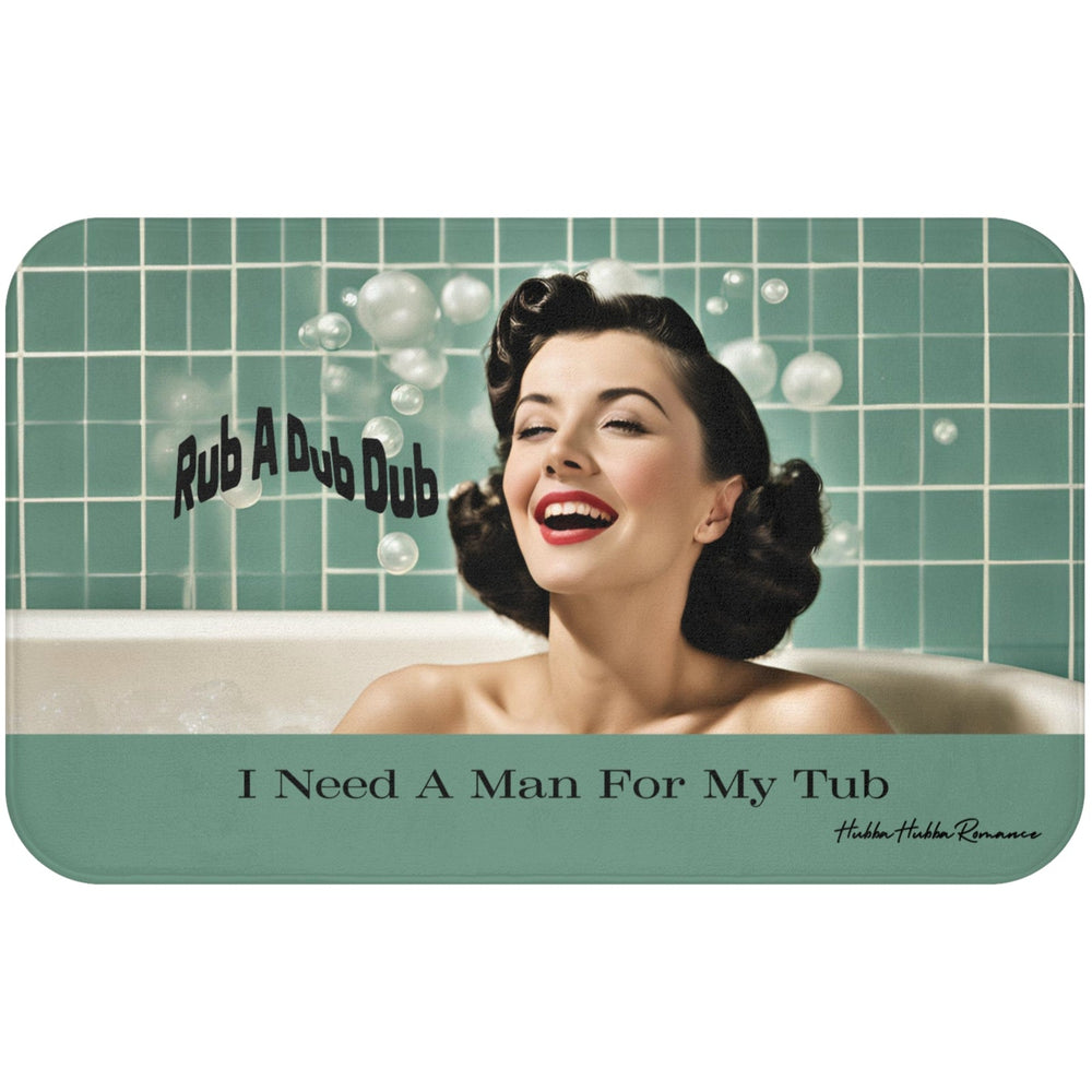 This bath mat features a retro-style image of a glamorous woman with styled dark hair, red lipstick, and a joyful smile, lounging in a bubble bath. Behind her is a sea-green tiled bathroom wall with soap bubbles floating around. Playful black text reads “Rub A Dub Dub.” At the bottom of the mat, centered over a seafoam green background strip, bold black text reads: “I Need A Man For My Tub.” The overall vibe is vintage pin-up with playful humor. This is the larger version.