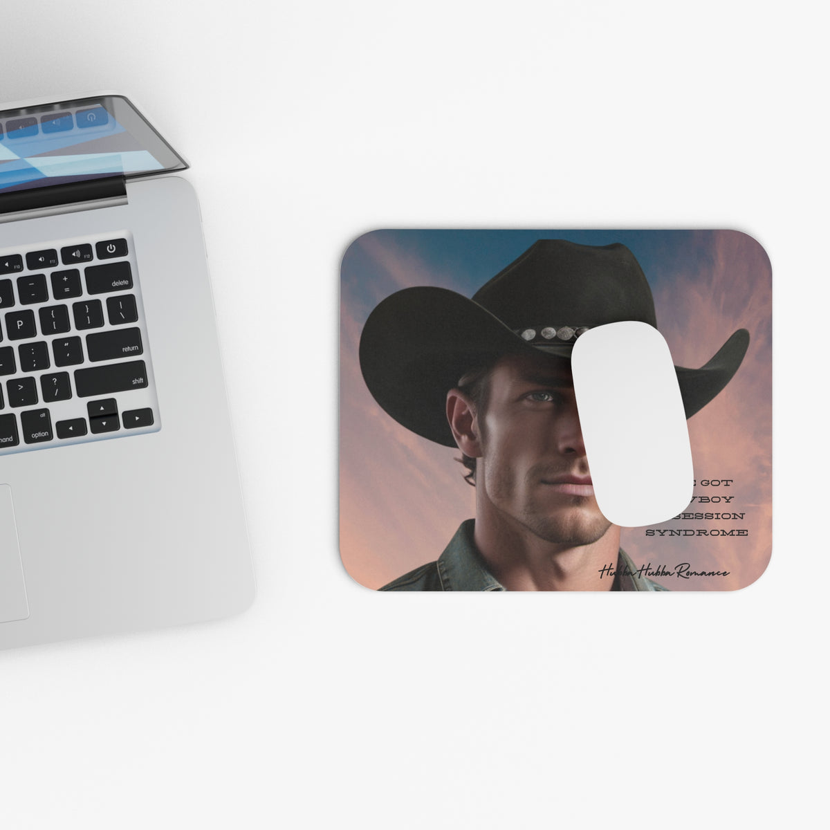 Computer mouse on the cowboy mouse pad next to a laptop on a white surface.
