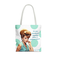 A white  tote bag with white shoulder straps, featuring a retro-style illustration of a woman with a large blonde bouffant hairstyle and a mint green polka dot background. The text on the bag reads, 'It's not considered hoarding if they're romance novels.