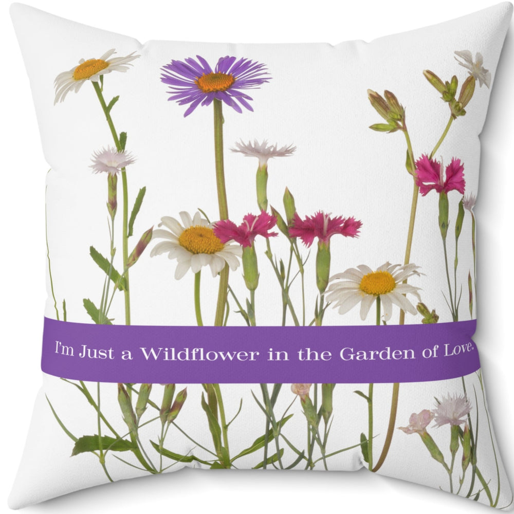 A 20-inch pillow that features a collection of wildflowers, including daisies, pink carnations, and a prominent purple aster, set against a clean white background. A horizontal purple banner stretches across the center, displaying the phrase "I'm Just a Wildflower in the Garden of Love." in white text. The design has a soft, romantic feel, evoking themes of individuality, natural beauty, and love.