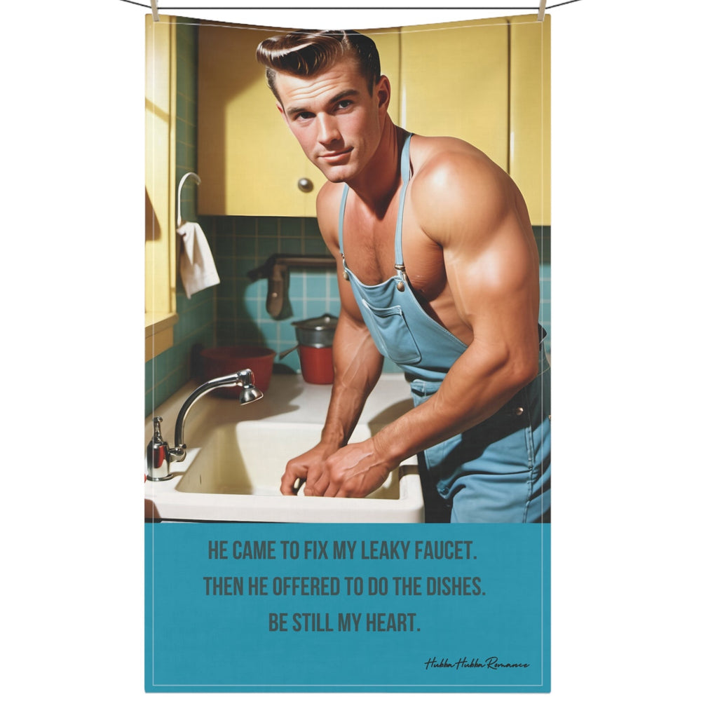 The image features a kitchen towel with a playful romance-themed design hanging on a clothesline secured by clothespins. The towel features a light background with a vintage-style illustration of a rugged, handsome plumber in a tool belt, smirking as if he knows exactly what he's doing. Across the jar, the text reads "The Plumber Stole My Heart" in bold, cheeky lettering. The design incorporates warm, earthy tones, adding a retro feel. The towel blends humor, sass, and romance, perfect for book lovers with 