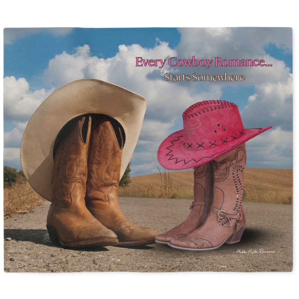 A sweatshirt blanket featuring a western-themed scene with a tan cowboy hat resting on brown leather boots on the left, and a bright pink cowboy hat perched on pink leather boots on the right, under a blue sky with clouds. Text at the top reads, 'Every Cowboy Romance Starts Somewhere.