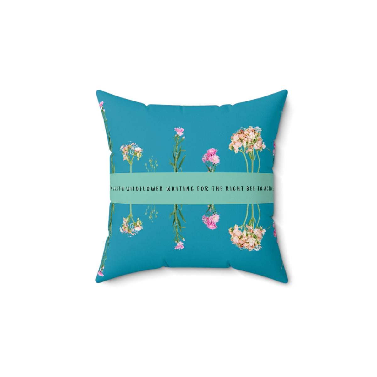 A 14-inch pillow that features an arrangement of delicate wildflowers, some upright and others hanging upside down, against a vibrant teal background. A horizontal light green banner stretches across the center, displaying the phrase "I'm just a wildflower waiting for the right bee to notice." in black text. The design is whimsical and romantic, symbolizing patience, individuality, and the hope of finding the perfect match.