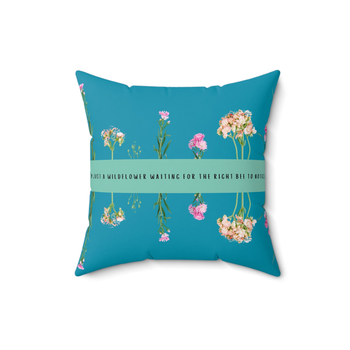 A 16-inch pillow that features an arrangement of delicate wildflowers, some upright and others hanging upside down, against a vibrant teal background. A horizontal light green banner stretches across the center, displaying the phrase "I'm just a wildflower waiting for the right bee to notice." in black text. The design is whimsical and romantic, symbolizing patience, individuality, and the hope of finding the perfect match.