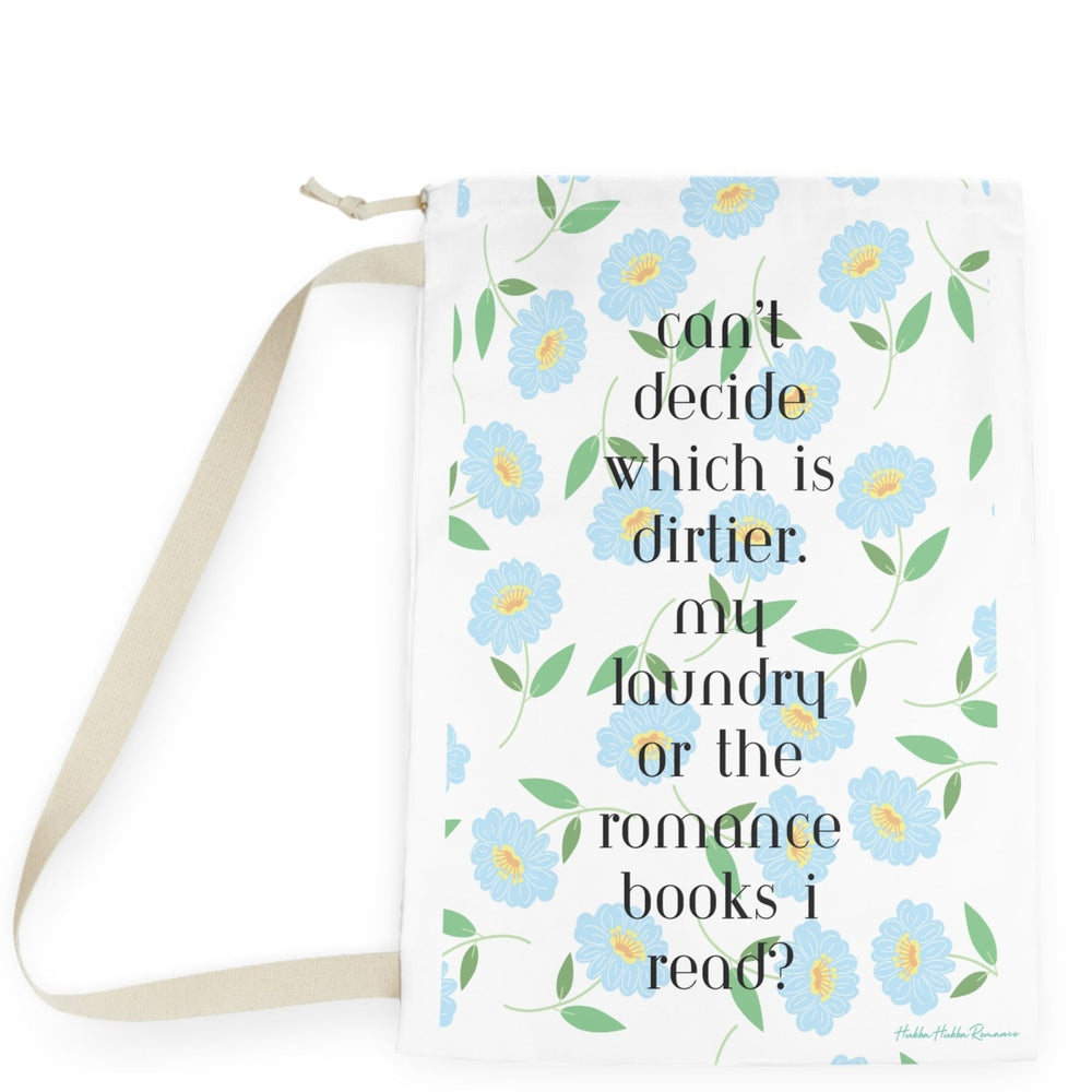 This design features a repeating pattern of light blue daisy-style flowers with yellow centers and green leaves on a white background. In the center, black serif text reads: “Can’t decide which is dirtier: my laundry or the romance books I read?” The floral pattern gives the design a soft, feminine touch, while the text delivers a cheeky, flirtatious message. The overall look is clean and pretty with a spicy twist for romance readers. There is a drawstring enclosure and a large canvas carry strap. 