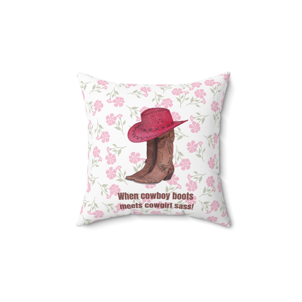 This 14 inch square pillow features a pair of brown leather cowboy boots with intricate stitching and metal accents, topped with a red cowboy hat with black stitched detailing. The background is soft white with a delicate pink floral pattern. Below the boots and hat, the bold brown text reads: "When cowboy boots meets cowgirl sass!" The design combines Western charm with a playful, feminine flair.
