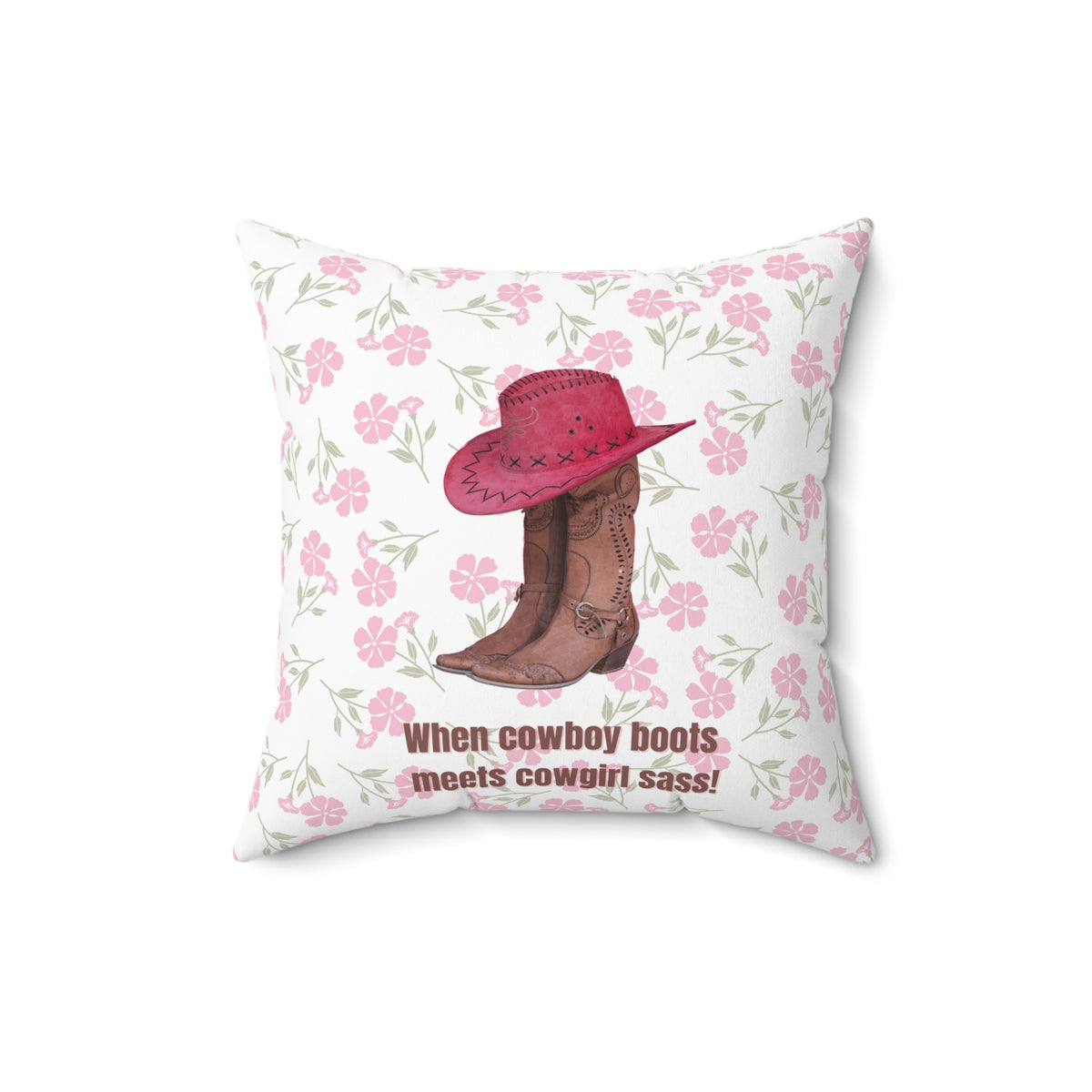 This 16 inch square pillow features a pair of brown leather cowboy boots with intricate stitching and metal accents, topped with a red cowboy hat with black stitched detailing. The background is soft white with a delicate pink floral pattern. Below the boots and hat, the bold brown text reads: "When cowboy boots meets cowgirl sass!" The design combines Western charm with a playful, feminine flair.