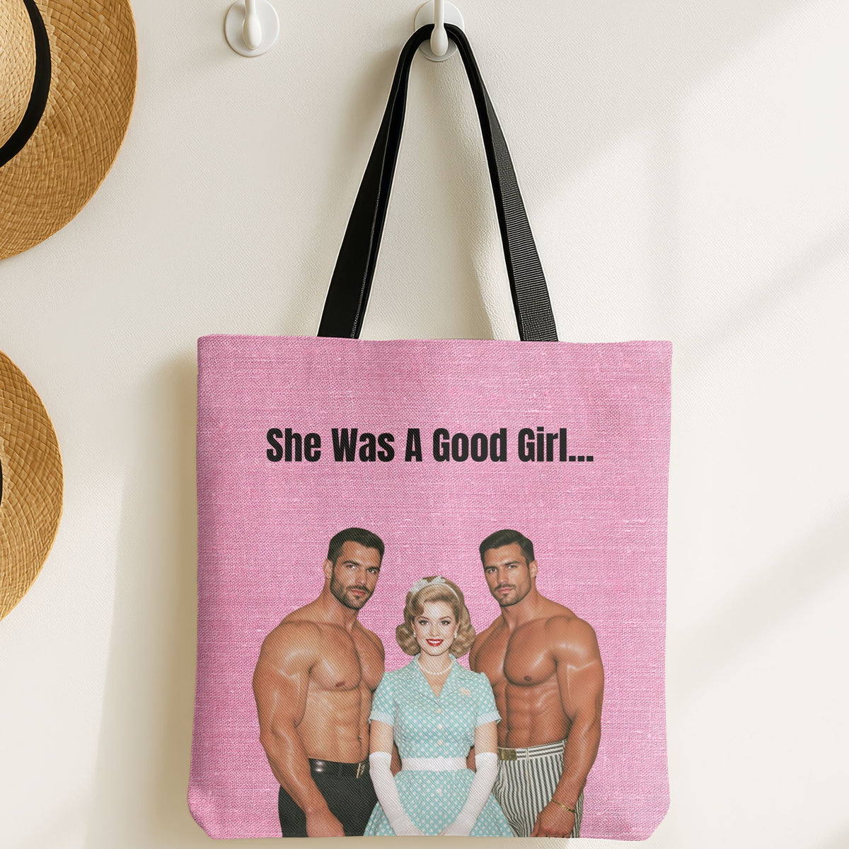 The tote bag is displayed on a wall hook with straw hats nearby.