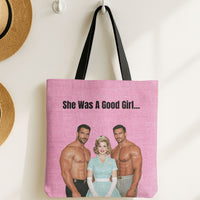 The tote bag is displayed on a wall hook with straw hats nearby.