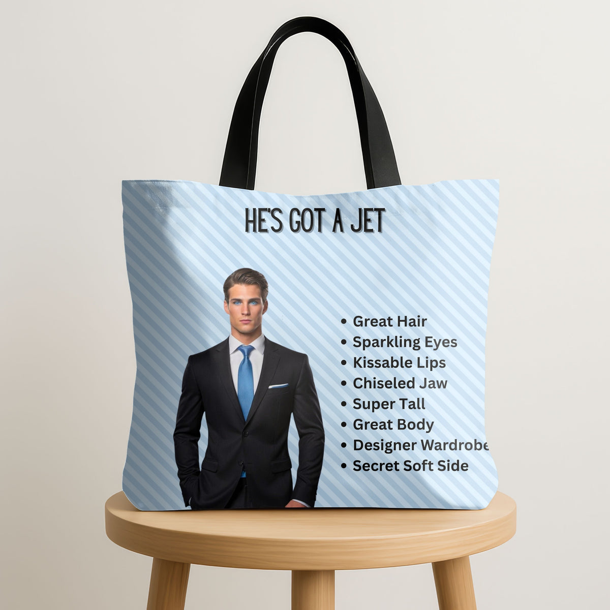 The Billionaire Boyfriend Tote is displayed standing upright on a wooden stool.

