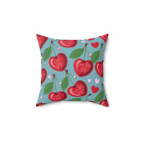 A 14-inch pillow features a playful pattern of heart-shaped cherries with green leaves and stems against a light blue background. Scattered among the cherries are small red and pink hearts. Each cherry is adorned with elegant white cursive text that alternates between "Love Me" and "Love Me Not," evoking the classic game of romantic uncertainty. The whimsical, romantic design combines a sweet aesthetic with a touch of flirtatious fun.