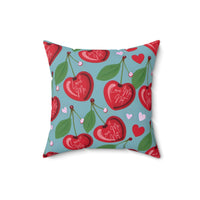 A 16-inch pillow features a playful pattern of heart-shaped cherries with green leaves and stems against a light blue background. Scattered among the cherries are small red and pink hearts. Each cherry is adorned with elegant white cursive text that alternates between "Love Me" and "Love Me Not," evoking the classic game of romantic uncertainty. The whimsical, romantic design combines a sweet aesthetic with a touch of flirtatious fun.