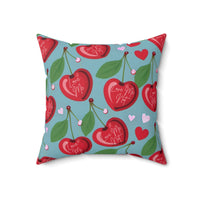A 18-inch pillow features a playful pattern of heart-shaped cherries with green leaves and stems against a light blue background. Scattered among the cherries are small red and pink hearts. Each cherry is adorned with elegant white cursive text that alternates between "Love Me" and "Love Me Not," evoking the classic game of romantic uncertainty. The whimsical, romantic design combines a sweet aesthetic with a touch of flirtatious fun.