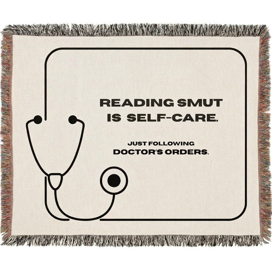 A woven cotton throw blanket with fringed edges, featuring a black stethoscope graphic and the text 'READING SMUT IS SELF-CARE. JUST FOLLOWING DOCTOR'S ORDERS.