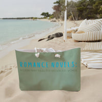 The weekender bag is displayed standing upright on the beach next to beach towels.

