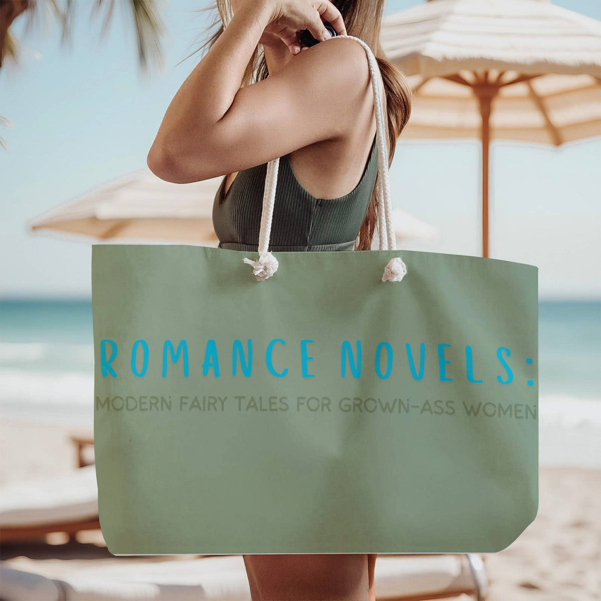 The tote bag is being modeled by a woman in a green tank top, standing on the beach, wearing it over her shoulder.

