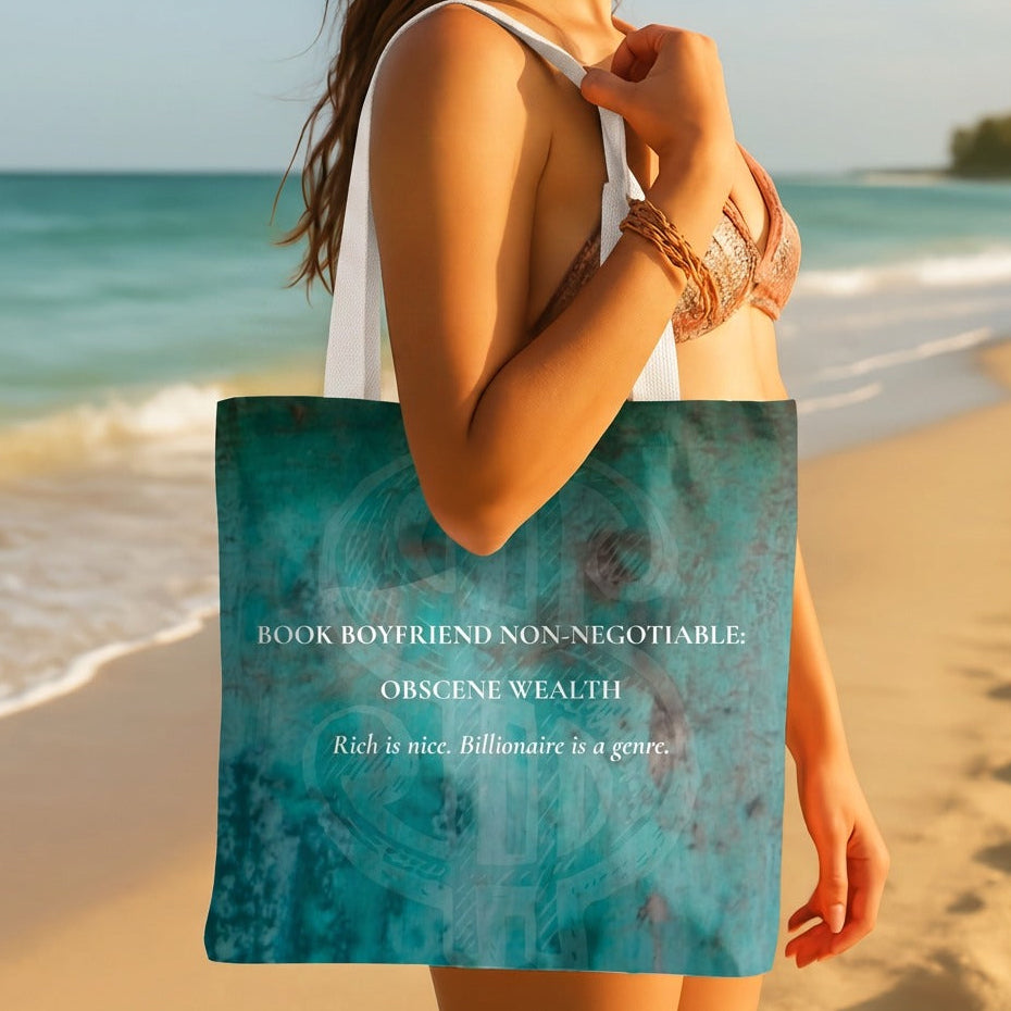 A woman on a sandy beach holds a teal tote bag with white text that reads, 'BOOK BOYFRIEND NON-NEGOTIABLE OBSCENE WEALTH Rich is nice. Billionaire is a genre.