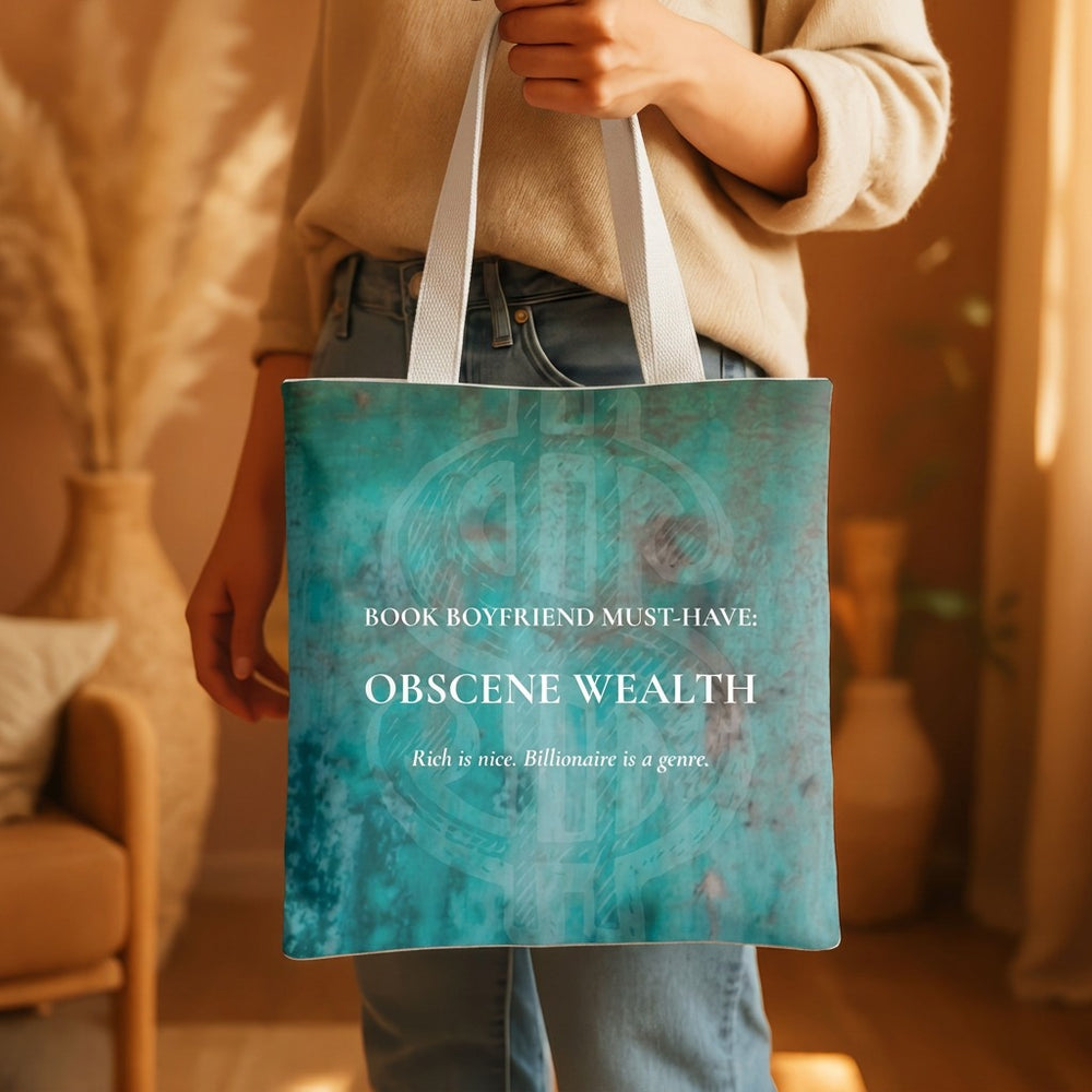 A person holding a distressed teal tote bag with white handles in a warm indoor setting. The bag has white text reading 'BOOK BOYFRIEND MUST-HAVE: OBSCENE WEALTH' and smaller text below.