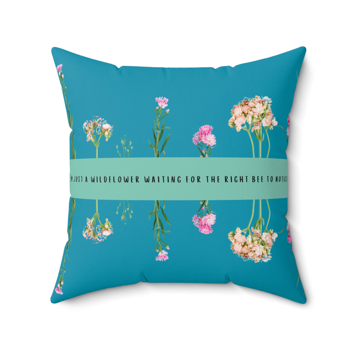 Square pillow with teal background, wildflower arrangement, and text on green banner: “I’m just a wildflower waiting for the right bee to notice.”