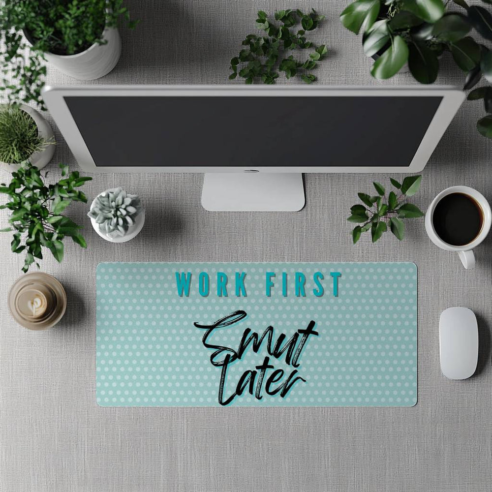Desk setup with a mouse pad featuring 'Work First, Smut Later' text, surrounded by office items.