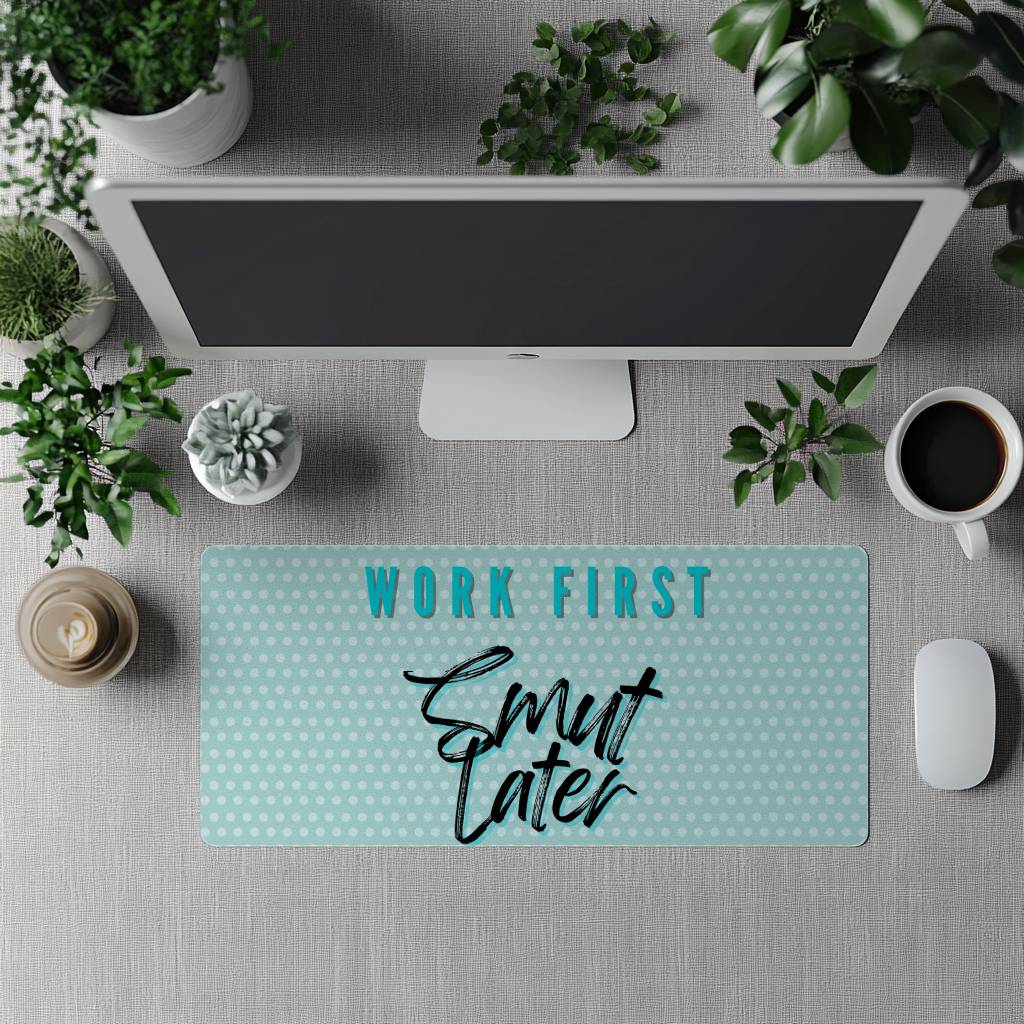 Desk setup with a mouse pad featuring 'Work First, Smut Later' text, surrounded by office items.