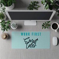 Desk setup with a mouse pad featuring 'Work First, Smut Later' text, surrounded by office items.