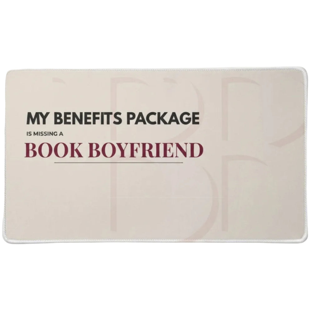 A rectangular desk pad  on a light tan background, featuring the text 'MY BENEFITS PACKAGE IS MISSING A'  in charcoal and  "BOOK BOYFRIEND' in dark red lettering.