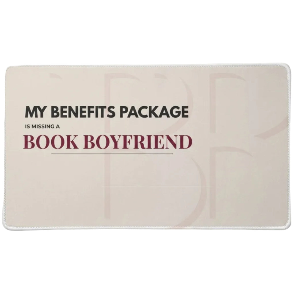 A rectangular desk pad  on a light tan background, featuring the text 'MY BENEFITS PACKAGE IS MISSING A'  in charcoal and  "BOOK BOYFRIEND' in dark red lettering.
