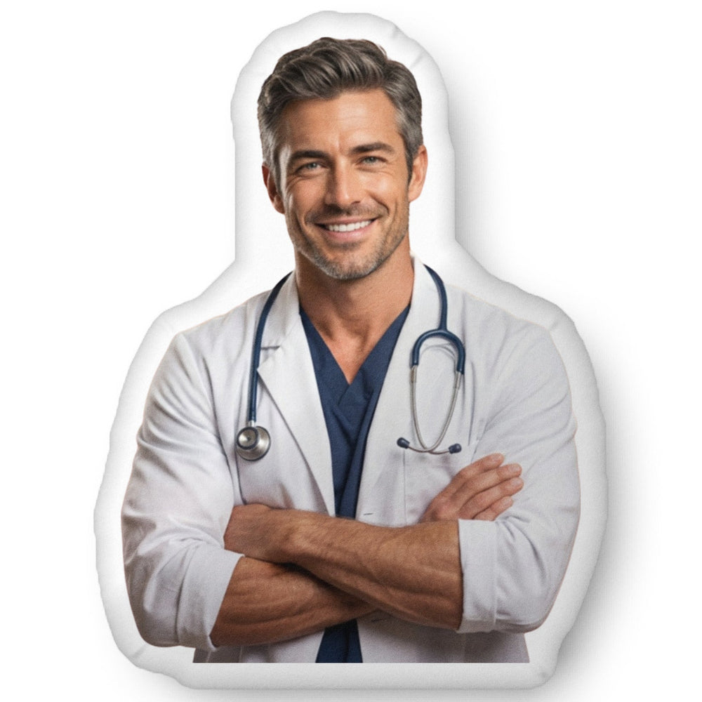 Custom-shaped decorative pillow featuring The Doctor, a handsome medical romance book boyfriend with salt-and-pepper hair, light stubble, and a confident smile, wearing a white lab coat with a stethoscope and folded arms. Shown as a standalone pillow against a neutral background. This medical romance book boyfriend pillow is available in three sizes (10" x 10", 16" x 16", and 22" x 22").