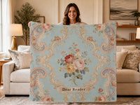 Woman holding a Regency-inspired sweatshirt blanket featuring vintage floral artwork, ornate scrollwork, and the phrase "Dear Reader." Elegant reading blanket in soft French blue designed for romance readers, historical romance fans, and book lovers.