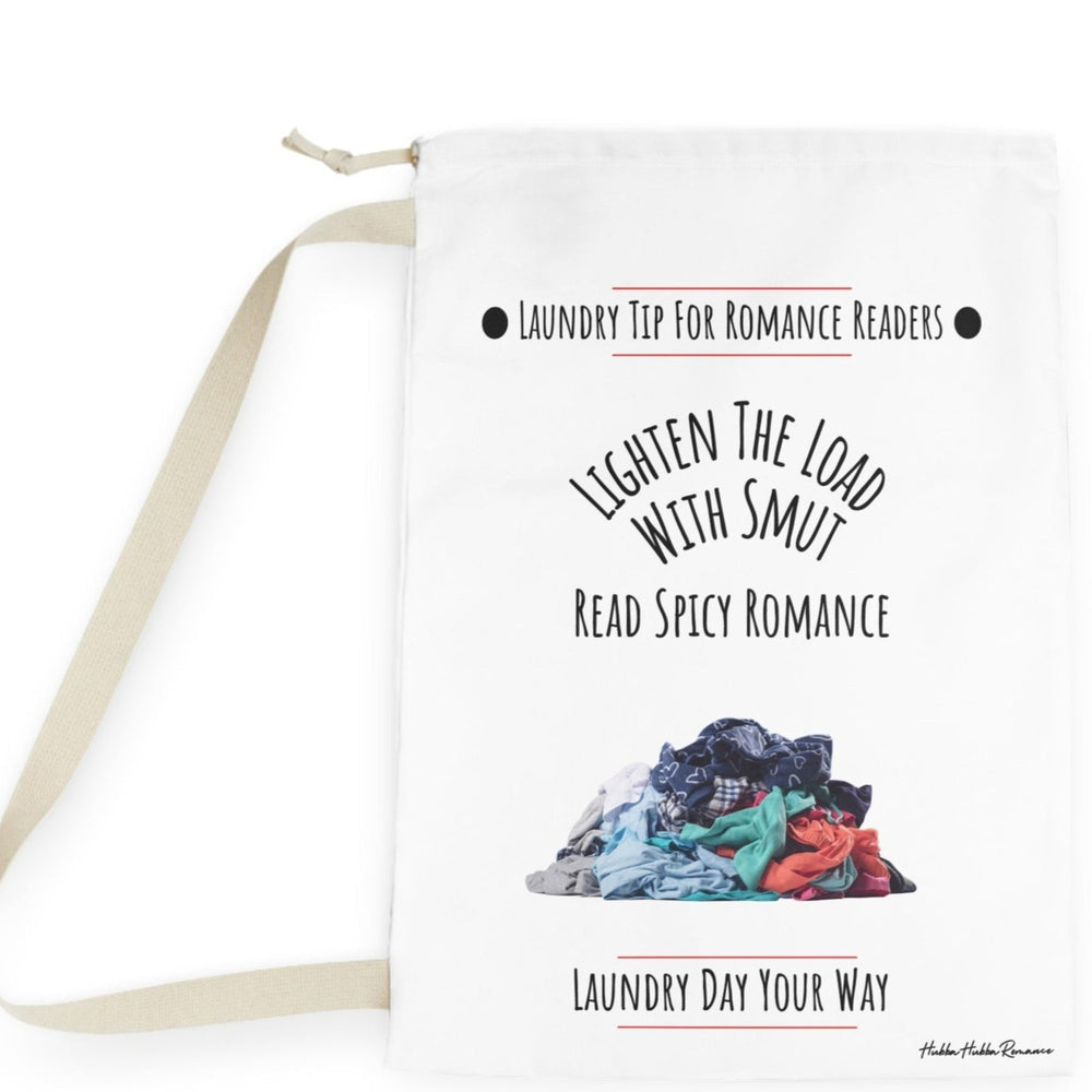 This laundry bag features a white background with a colorful pile of clothes  at the bottom. Above the pile, black text reads: “Lighten the Load with Smut” in an arched layout. Below that, in a straight line, it says: “Read Spicy Romance.” At the top, the header “Laundry Tip for Romance Readers” is centered between two black dots and underlined in red. The bottom of the image reads: “Laundry Day Your Way” in black text, underlined in red. The bag includes a drawstring closure and a canvas carry strap.
