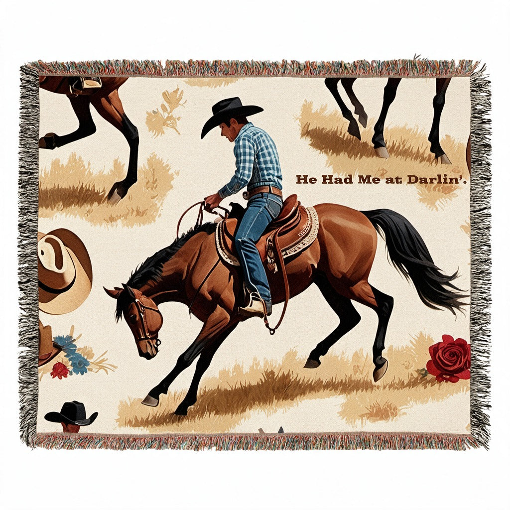 Cream fringed woven blanket featuring a cowboy riding a brown horse, Western hats, flowers, and the words “He Had Me at Darlin’.”