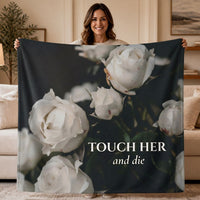 A woman stands in a living room holding up a 50" x 60" sweatshirt blanket featuring a dark background with large white roses and the text 'TOUCH HER and die'.